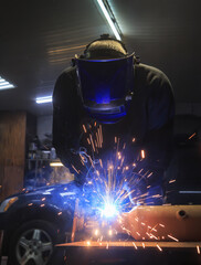 Welder welds a car part in workshop - 680284743