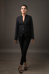a business woman standing in black suit giving bold look depicting luxury and fashion on black background 