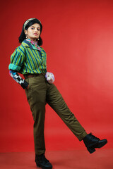 beautiful female model in striped green and black shirt and brown trousers