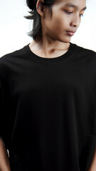 Clothing model. Young Asian man with long curly hair close up shot isolated on white. Asian young man wearing plain black t-shirt isolated on white background. As if he were modeling a plain t-shirt.