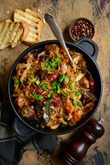 Bigos - traditional dish of polish cuisine,stewed cabbage with meat, sausage and dried mushrooms in a pan . Top view with copy space.