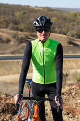 Cyclist riding bicycle on offroad against clear sky. A man in an outfit stands with a bicycle on an autumn sunny day.