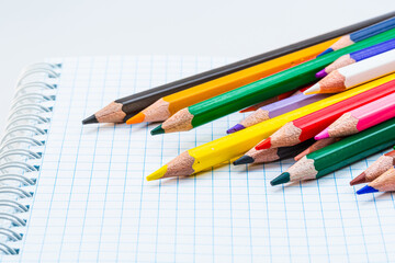Fototapeta premium A Rainbow of Creativity: Colored Pencils Resting on a Notebook. A group of colored pencils sitting on top of a notebook