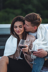 Romantic beautiful surprise on Saint Valentine's Day for a girlfriend. Loving young couple having dinner on a rooftop on sunset evening with candles, wine. Skyscrapers on background, urban cityscape