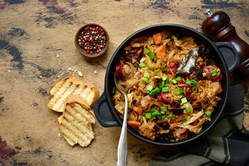 Bigos - traditional dish of polish cuisine,stewed cabbage with meat, sausage and dried mushrooms in a pan . Top view with copy space.
