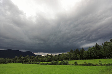 Dunkle Regenwolken &uuml;ber einer gr&uuml;nen Wiese