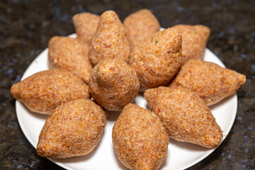 Traditional meat kibbeh (kibe), typical food from the middle east, typical turkish, syrian or arabic food, savory from arabic cuisine on white background with selective focus (kibe)