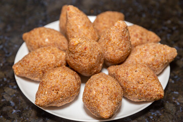 Traditional meat kibbeh (kibe), typical food from the middle east, typical turkish, syrian or arabic food, savory from arabic cuisine on white background with selective focus (kibe)