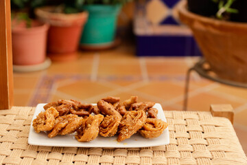 Moroccan chebakias on a white plate in a patio with plants