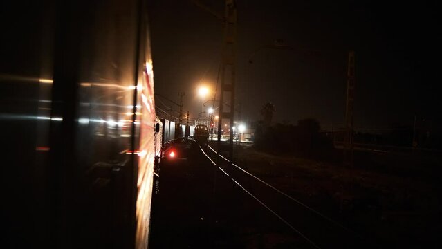 Illuminated railway station and arriving trains on platform in night time