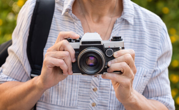 Retro film photo camera in female hands outdoors