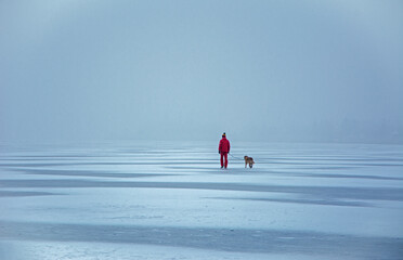 The man in red and the dog on the frozen lake.