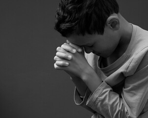 boy praying to God with hands held together with people sock image stock photo	
