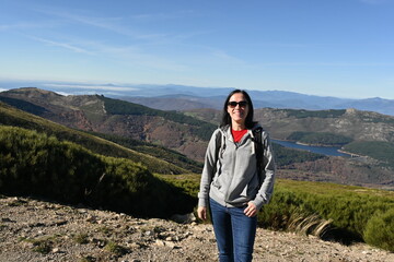 Naklejka premium Smiling woman wearing sunglasses with a panoramic view of mountains behind her