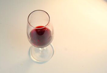A photo of red wine in a small wine glass on a white surface. 