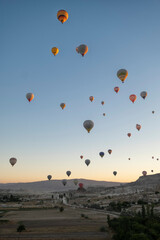 numerous hot air balloons flying over the fairy chimneys, at the Goreme airfield at dawn, Cappadocia, Turkey, vertical