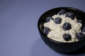 Close up of cottage cheese with fresh blueberries in black bowl, hight protein dessert