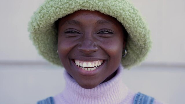 Close-up young african woman face smile at camera over urban background. Positive people and diversity concept.