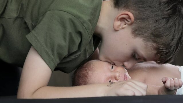 Older brother kisses his newborn brother on the cheek. Happy family. Happy newborn baby with his brother.