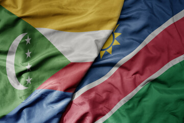 big waving national colorful flag of namibia and national flag of comoros .