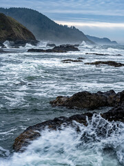 Waves splash against the basalt slabs along the shore of the Pacific Ocean near Florence, Oregon, USA