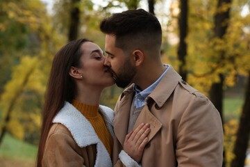 Happy young couple kissing in autumn park