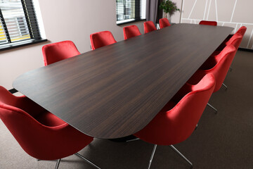 Empty conference room with stylish red office chairs and large wooden table - Powered by Adobe
