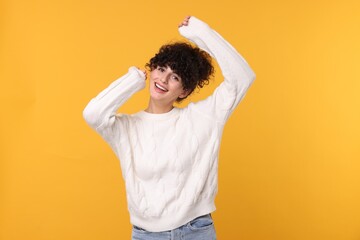 Happy young woman in stylish white sweater on yellow background