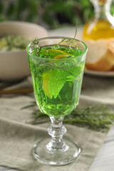 Delicious drink with tarragon in glass on white table