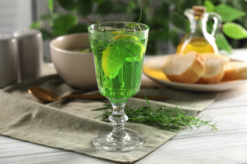 Delicious drink with tarragon in glass on white wooden table