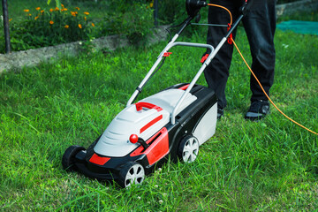 Man cutting grass with lawn mower in garden, closeup