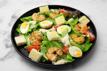 Delicious Caesar salad with shrimps on white marble table, closeup