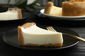 Piece of tasty vegan tofu cheesecake and fork on black wooden table, closeup