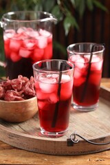 Delicious iced hibiscus tea and dry flowers on wooden table