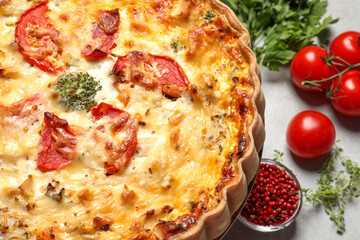Tasty quiche with tomatoes and cheese served on light table, closeup