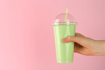 Woman with plastic cup of tasty smoothie on pink background, closeup. Space for text