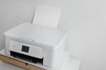 Fototapeta premium Modern printer with paper on table near white wall, space for text