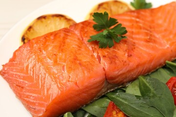 Tasty grilled salmon with basil and parsley on white plate, closeup
