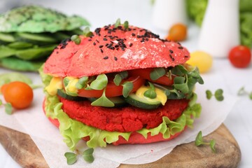 Tasty pink vegan burger with vegetables, patty and microgreens on white table, closeup