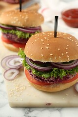 Tasty vegetarian burgers with beet patties on white marble table, closeup