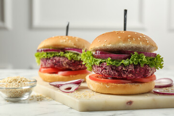 Tasty vegetarian burgers with beet patties on white marble table, closeup