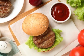 Delicious fried patty, lettuce, buns and sauce on wooden table, flat lay. Making hamburger