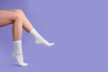 Woman in stylish white socks on violet background, closeup. Space for text