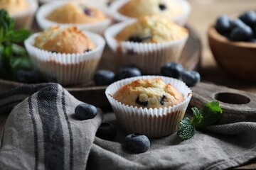 Delicious sweet muffins with blueberries and mint on table, closeup