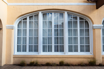 Close up of large arched window in old building with white wood frame and beige stucco