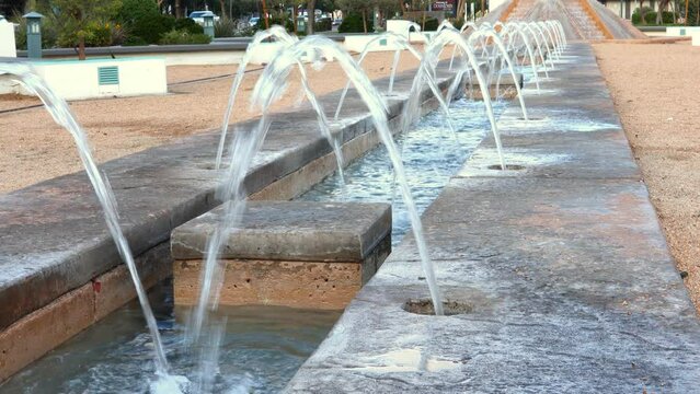 Long water feature fountain in public park, multiple spouts, stationary view, copy space, 