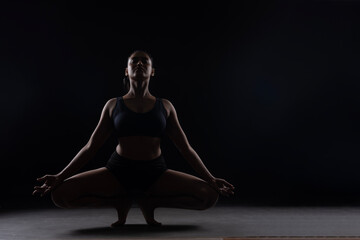 Fit Women Performing Yoga Postures Depicting Fitness in dull light and black background wearing black sports wear 