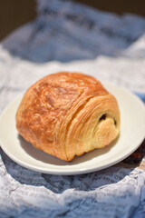 Close up Chocolat Croissant on news papers background- yeasted puff pastry dough wrapped around a stick of chocolate