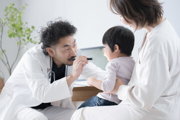 小児科医の男性医師に診察を受ける子ども　口をあける