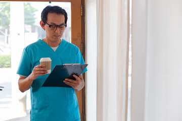 Smiling nurse using digital tablet in employee lounge. Happy nurse resting on couch in lounge area and drinking cup of coffee.